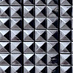 A close-up view of a grid of metallic, square, pyramid-shaped studs creating a geometric, reflective pattern.