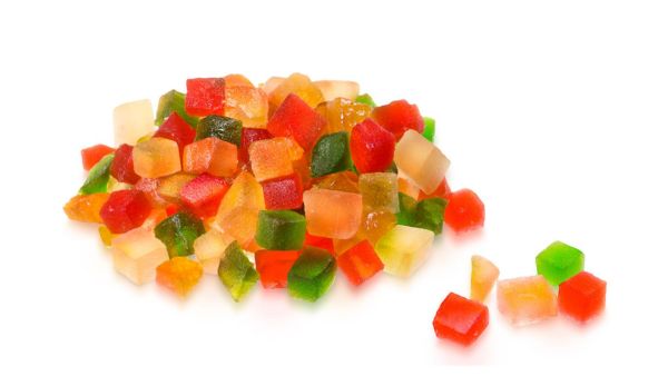 A pile of colorful candied fruit cubes, including red, green, orange, and yellow pieces, on a white background.